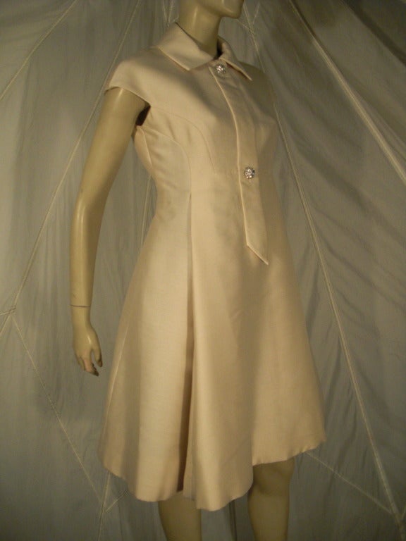 A fabulous 1960s Geoffrey Beene vanilla silk button-down style dress with collar and cap sleeves, front placket and deeply pleated A-Line skirt.  Concealed front zipper. Completely lined.