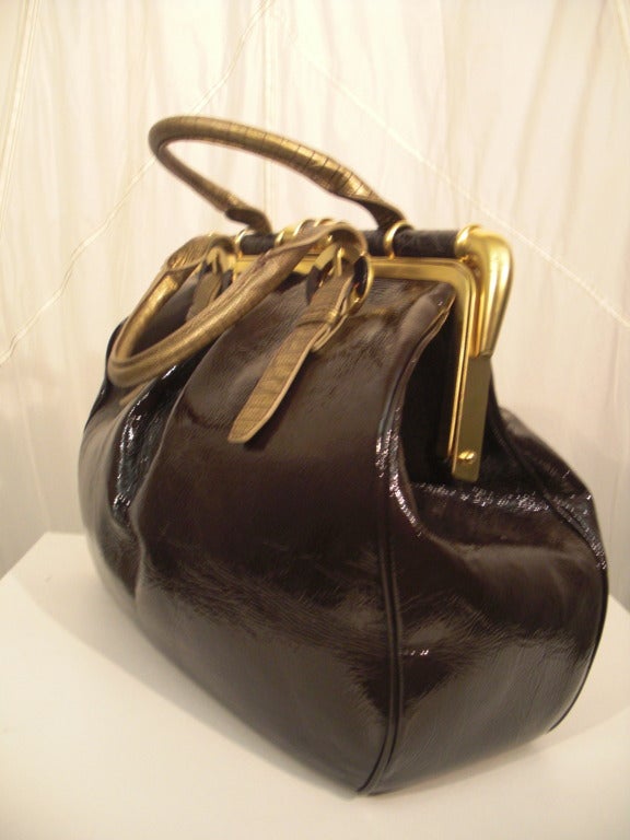 A gorgeous mocha brown patent leather doctors bag with gilt leather handle straps, gold-tone barrel hardware, and faux tortoise shell and alligator trim.  Gold feet are in perfect condition.  Lining is excellent.  Straps are adjustable with buckles.