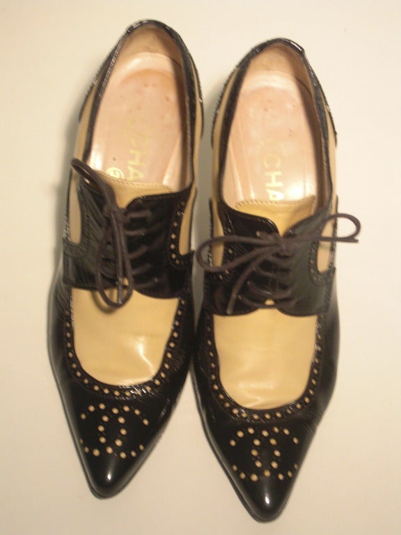 A great pair of Chanel tan and black patent leather lace-up stiletto oxfords: Chanel logo perforated into the toe. Light wear to the heel lift, will need replacing.