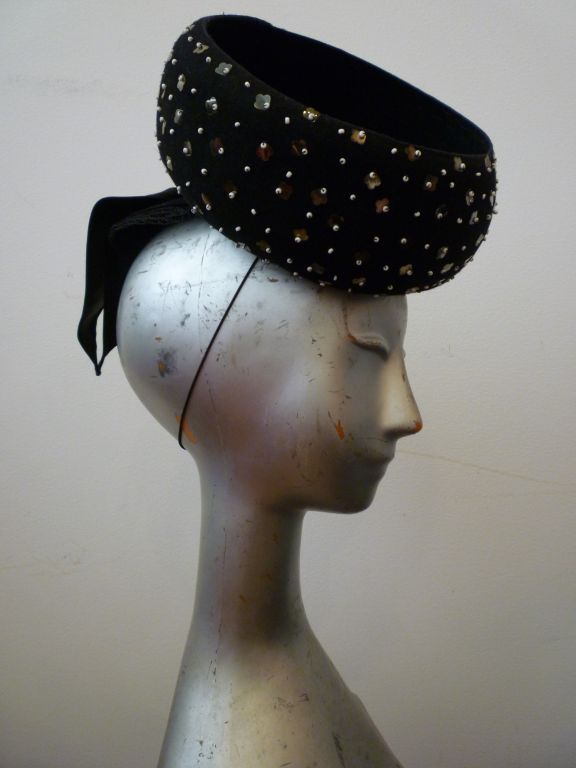 A divine 1940s hat with an exaggerated bowl shape embellished with sequins, beads and a bow at the back. Wonderfully stylized, it perches at a wonderfully impossible angle--totally 40s!  Marked 