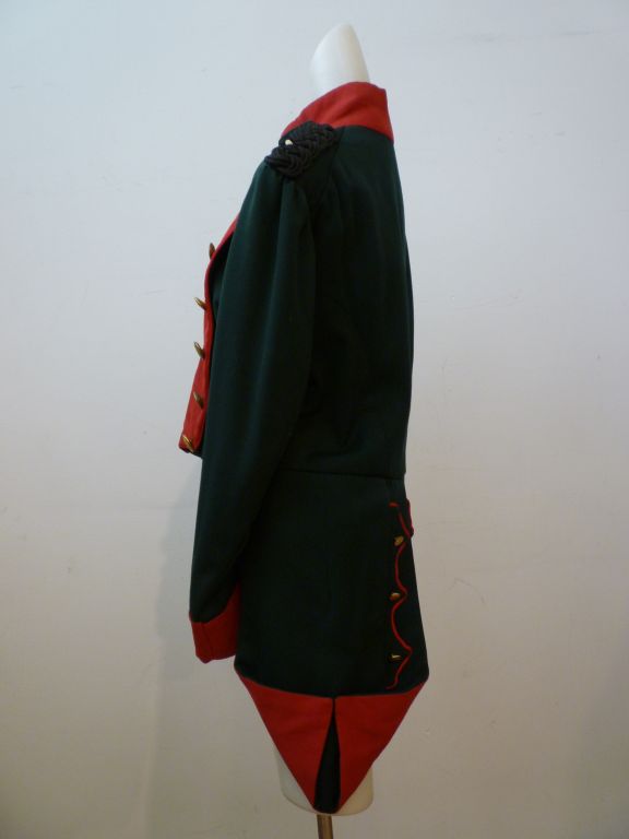 A great military band jacket (?) with wonderful details such as tails and loads of military insignia buttons!  Forest green and red with black braided epaulets and brass buttons.  Marked a size 40 chest.