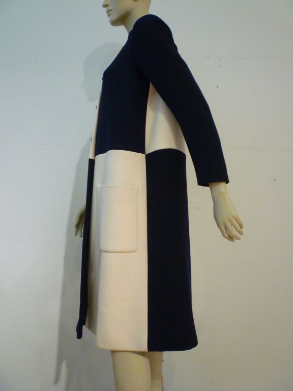 A wonderfully simple and chic Norman Norell 60s coat designed in quadrants of navy and cream wool with deep patch pockets and contrasting leather buttons.  The silk lining has a matching quadrant design!  Labeled NORELL and I. Magnin.