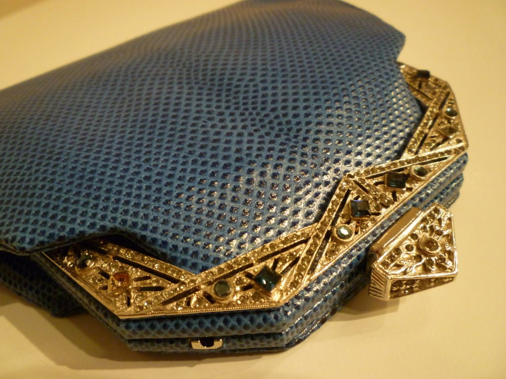 An elegant Judith Leiber 1980s blue lizard skin evening clutch (optional convertible strap) with Art Deco inspired jeweled frame.  Includes original accessories, mirror, coin purse and metal comb with tassel attached. Faille interior.