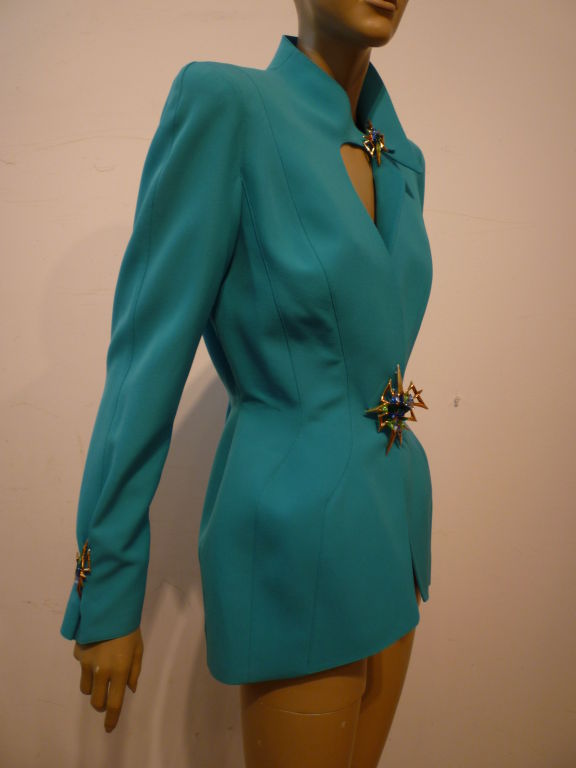 A fabulous example of the classic sculpted Mugler suit jacket in aqua gabardine embellished with beautiful aqua and peridot toned jewels at the waist, neck and cuffs!  Unusual asymmetrical neckline! Marked a French 40. Approx US 6