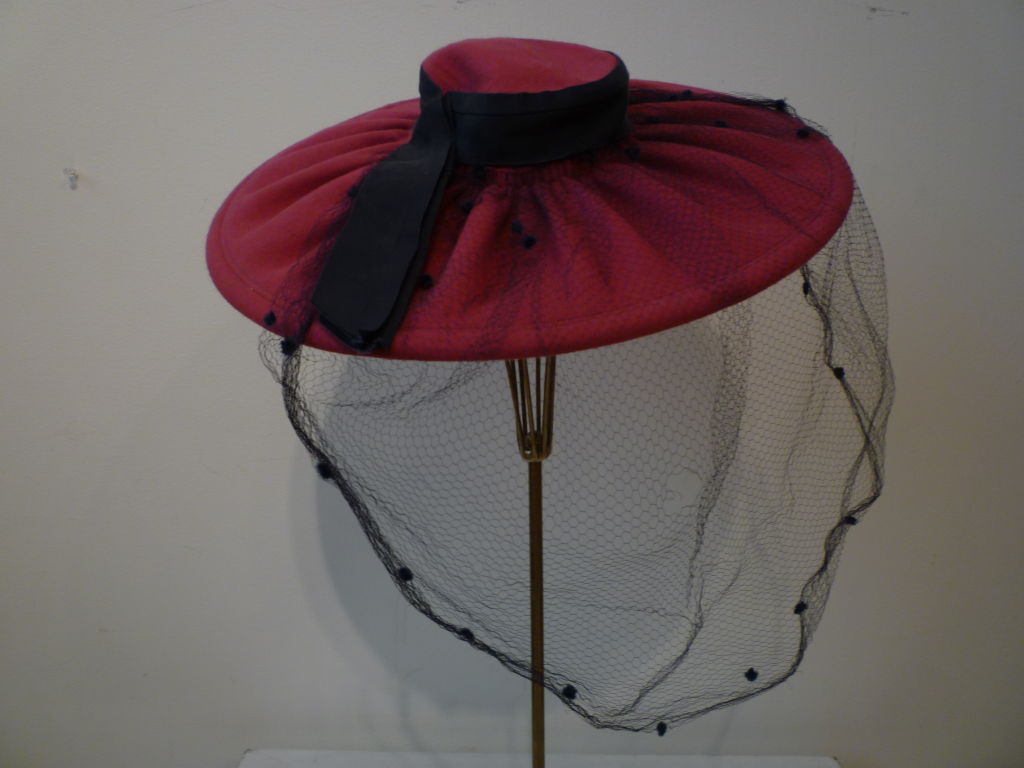A fantastically proportioned fuchsia felt hat with huge brim shallow crown and  deep pleating in the brim.  Wide grosgrain band with tulle veil.