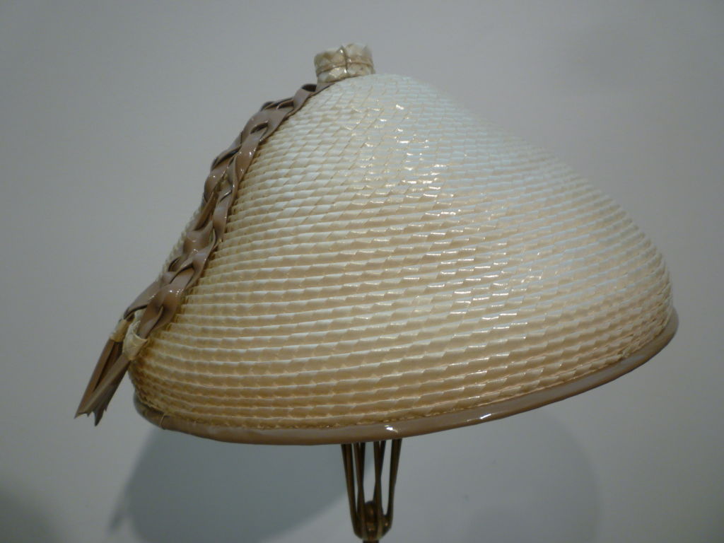A wonderful Marché hat from the 60s in beige straw with taupe vinyl piping and braid. Has an inner grosgrain banded piece that fits to the head. Such a great Asian-inspired shape!