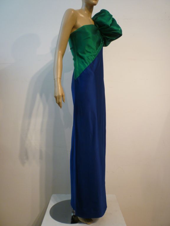 A fantastic 80s Bill Blass evening gown with a dramatic asymmetrical shoulder treatment in emerald green and royal blue silk satin.  Diagonal color block seaming in the boned and constructed bodice.