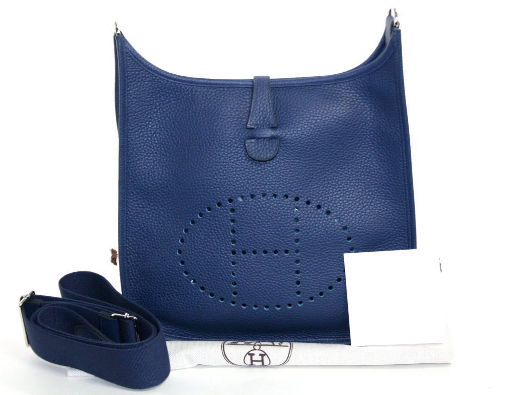 This authentic Hermès Blue Sapphire Evelyne PM is in pristine unworn condition with the protective plastic intact on the hardware.   The 2014 classic shade of blue complements nearly every other color and is a lovely addition to any comprehensive