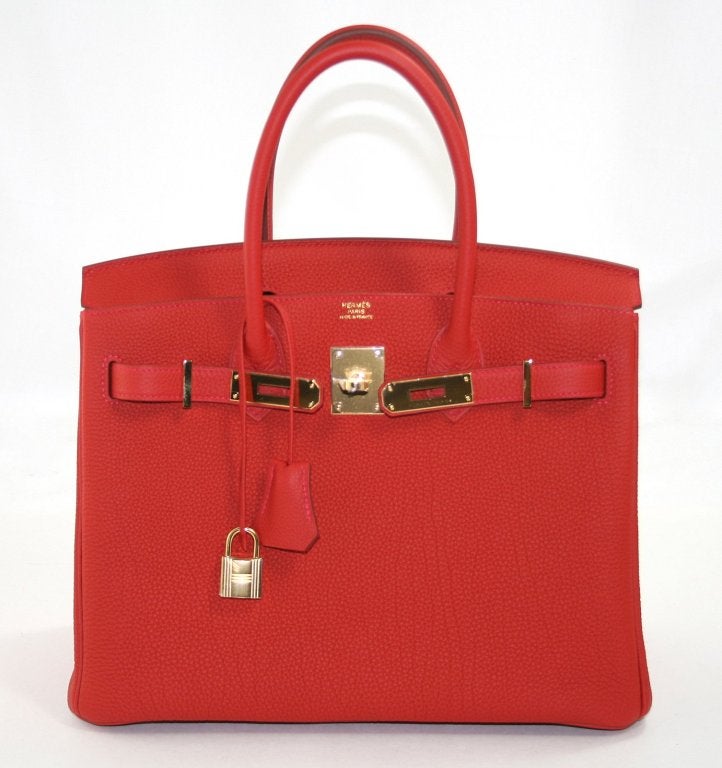 This authentic Hermès Vermillion Togo 30 cm Birkin has never been carried and is perfectly pristine. The protective plastic is intact on the hardware and is has been carefully stored with the felt.  Considered the ultimate luxury item the world over