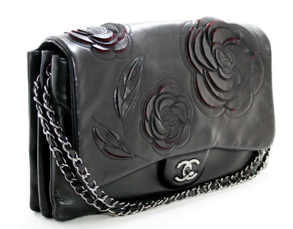Questa autentica borsa Chanel Black Lambskin Camellia Runway Flap è in ottime condizioni e non presenta segni significativi di precedenti proprietà.  Si tratta di un pezzo in edizione speciale, completamente esaurito e non più in produzione.
 
La