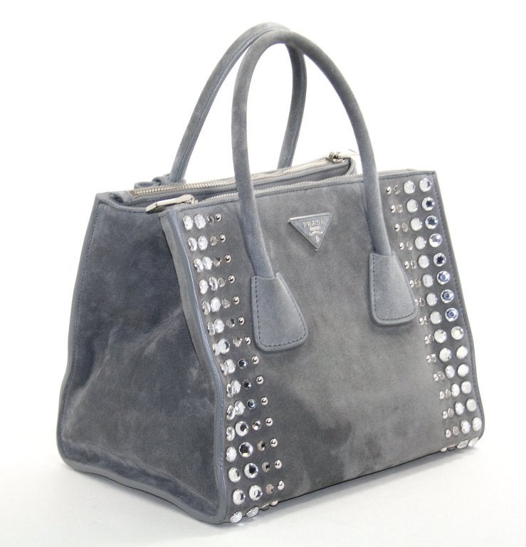 This Authentic Prada Grey Suede Studded Tote is in better than excellent overall condition.  There are minor scuffs on the bottom surface and light handle wear.  The corners and interior appear flawless.  Quite beautiful with a convertible shape and