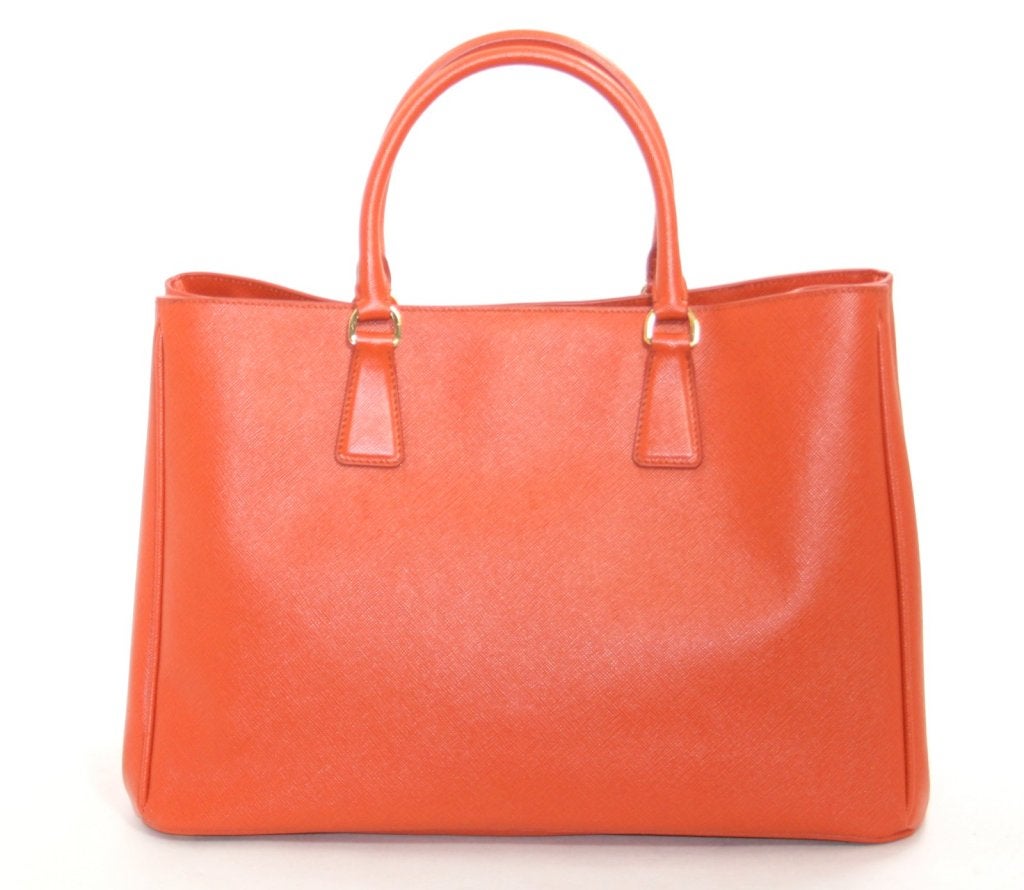 This Authentic Prada Papaya Saffiano Lux Leather Tote is a current style in mint condition.   The sophisticated silhouette is elegant and versatile; a brilliant addition to any collection in an exciting pop of vibrant orange.
 
Orange saffiano