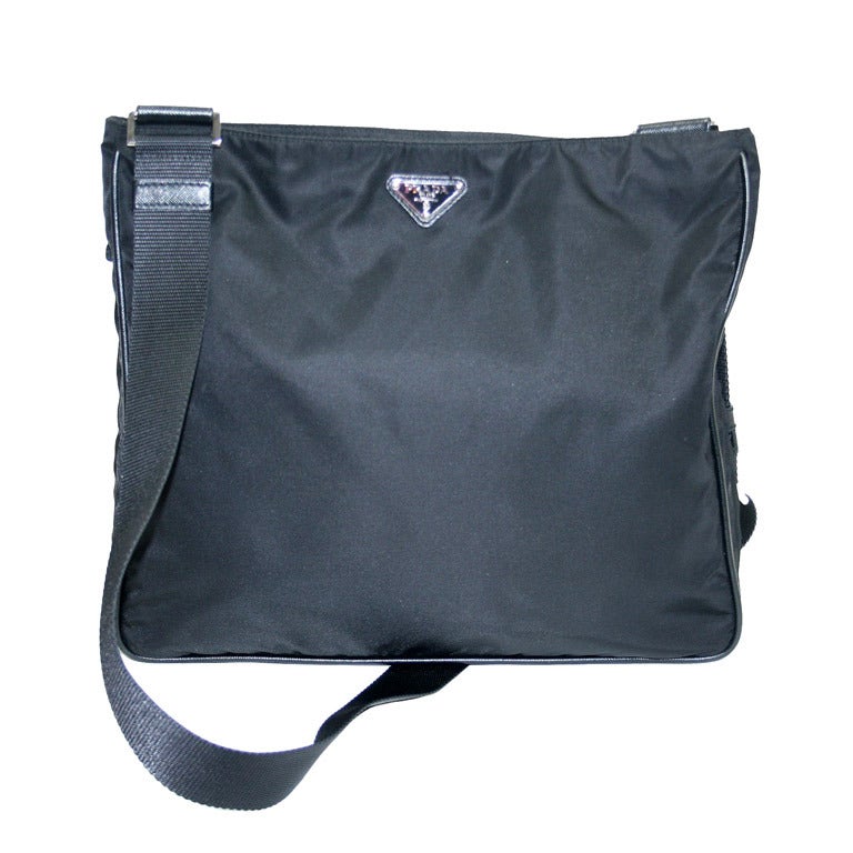 Narrow Choices Prada Black Vela nylon Prada crossbody bag with silver-tone hardware, tonal woven adjustable flat shoulder strap, single zip pocket and logo placard at front, tonal nylon lining and zip closure at top.