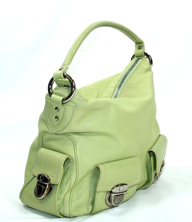 Vivid lime green leather is accented with silver tone hardware.  Signature Marc Jacobs engraved push locks secure each of the four exterior pockets.  Zippered top accesses the light pink fabric interior. Single leather strap may be snugly worn on