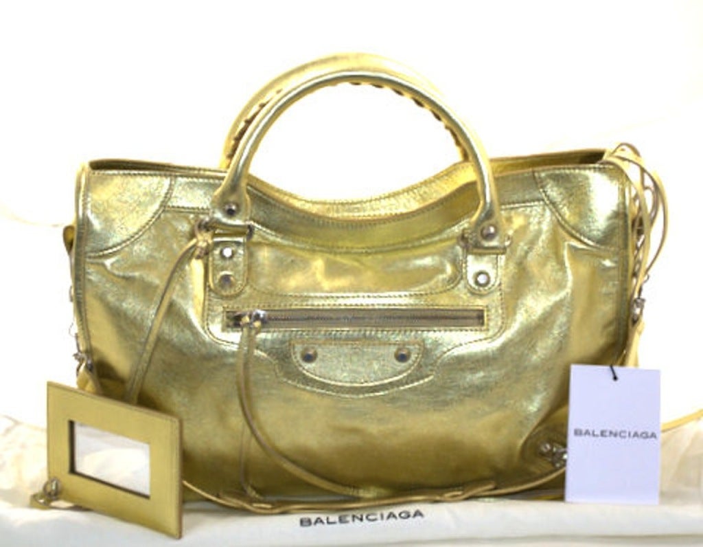 This authentic Balenciaga Gold City Bag is brand new.  The motorcycle inspired details are legendary.  This sexy metallic gold is a must have for collectors. 
 
  While Balenciaga is known for their simple iconic silhouettes, each season's vibrant