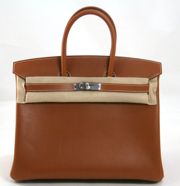 This authentic Hermès 35 cm Barenia Birkin is absolutely pristine and never carried. The protective plastic remains intact on the hardware and it has been carefully stored in the original box.    Considered the ultimate luxury item the world over