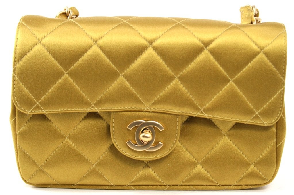 This authentic Chanel Mustard Satin Mini Classic Flap is in pristine unworn condition.  The petite silhouette and golden hue makes it incredibly versatile for day or evening wear.
 
Mustard yellow satin is quilted in signature Chanel diamond