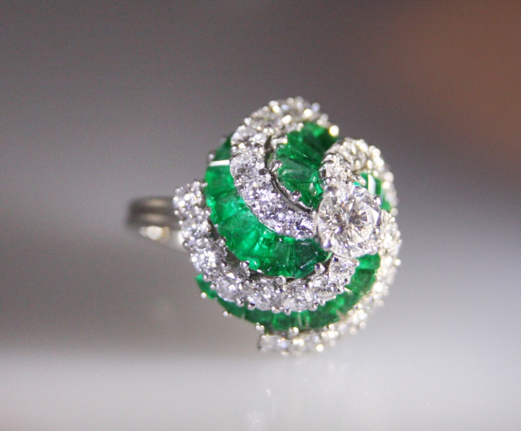 Oscar Heyman and Brothers ring is set with a round diamond in the center weighing approximately .80 carats. Further set with 32 diamonds weighing approximately 2.50 carats and tapering baguette cut emeralds weighing approximately 2.00 carats. 
Size