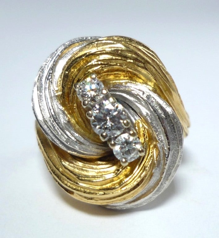 Swirls of White and Yellow Gold centred by 3 Brillant-cut diamonds.
US Size 6 3/4, European