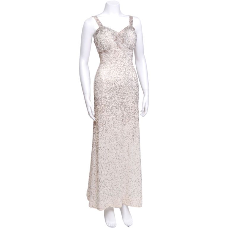 Ceil Chapman silver beaded cream silk crepe gown.  Has a bow design on the chest and am empire waist.  2 inch width straps.  Slight discoloration throughout bottom.