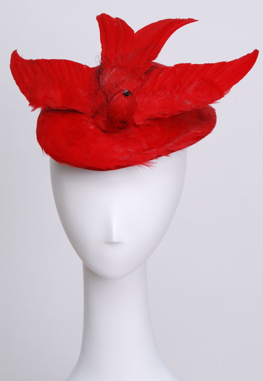 Rare, bright, shiny, red bird hat with fine black netting. The light weight hat sits atop of the head and is secured with an elastic ribbon. Kept in excellent condition.
