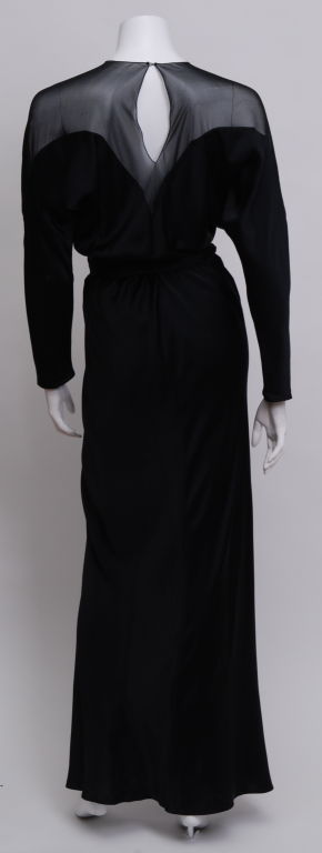 Black silk charmeuse long sleeve gown with silk chiffon inset. V-cut slit up the front to the knee. Tie belt.<br />
<br />
Halston<br />
Roy Halston Frowick, a studio 54 socialites, became a household name in 1962 when Jackie Kennedy wore one of