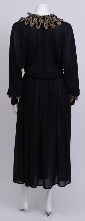 Black silk dress with a wrap style top and gathered skirt. Gold embroidered leaf pattern trim, from the 1983 fall collection. Donated by Lauren Bacall to the Brooklyn Museum in the late 1980's.
