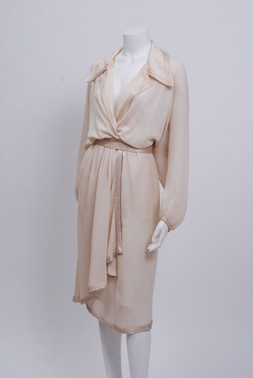 Cream colored silk chiffon dress, decorated with shiny satin silk embroidery and gold bugle beads. Tie wrap belt. Donated by Lauren Bacall in the late 80's to the Brooklyn Museum.