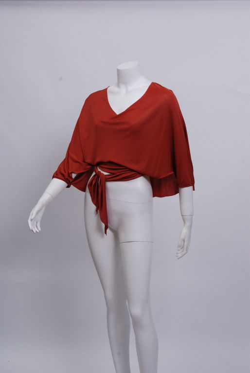 Burnt orange, three quarter length blouse with a wrap tie waist and cape back.<br />
<br />
Mrs. Harp captivated Hollywood with a rich hippie look in the 1960's and enthralled New York with soft clinging designs. She was nominated for Coty awards