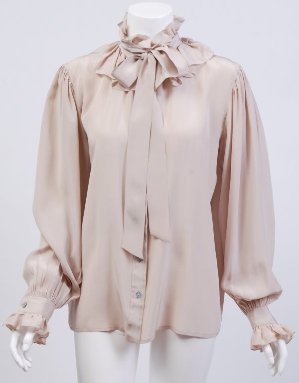 Cream silk ruffled blouse with mother of pearl buttons and tie neckline.