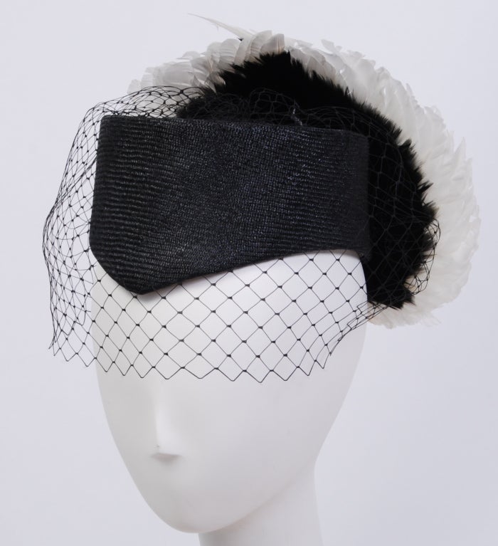 Stunning, one of a kind Jack McConnell straw and feather hat. Trimmed with black netting and decorated with two toned white and black feather wings. 
Packed in original box with notes for the buyer.