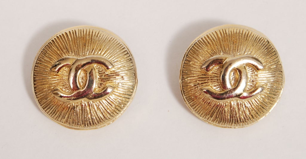 Shiny gold tone star-burst medallion ear clips with trademark interlocking C's.