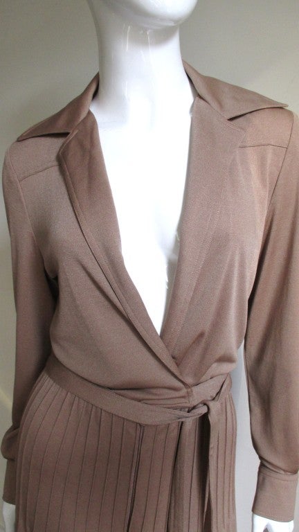 A tan wide leg, plunge to the waist, knit jumpsuit from home grown American celebrity designer Albert Capraro.  Front and back yokes, pointed collar with notched lapels open to the waist where an attached self belt crosses slightly to wrap around