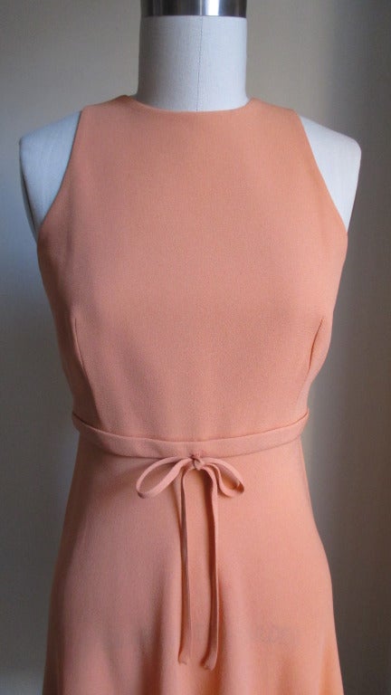 Vintage Gianni Versace Couture in a pretty peach colored silk.  It has a fitted waistband with a bow, cut in shoulders in the front and a feminine flared skirt.  The back has a triangular cutout from the waist and ending at the neck in ties.  Side