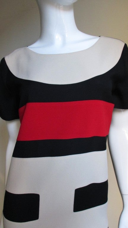 Simple short sleeved shift dress from Moschino ingeniously appliqued with the letters C H I C to spell Chic along the length of the dress with the last C creating the neckline.  A great combination of black, red and beige front and a black back of