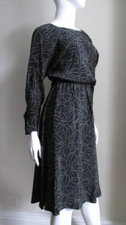 A great black wrap silk abstract leaf patterned dress from Halston.  The dress has a rounded front neck and a V in the back.  It wraps crossing at the back closing with black hooks at the waist.   It has dolman sleeves and the skirt is full.  The