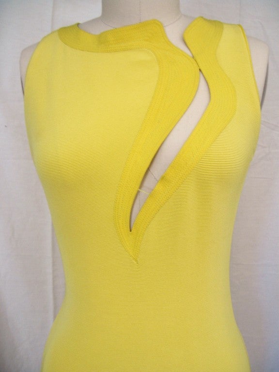 Lemon yellow knit form fitting dress from Versace. Curved slash extending from shoulder to below cleavage kept from revealing too much with delicate threads.  Multiple rows of topstitching detail around neckline, slash and hem.  Back zipper. Sizes