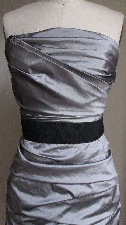 Silver silk taffeta bustier dress from Dolce & Gabbana.  The dress is ruched  down the sides and tacked into place.  The top portion is boned for fit and support.  The skirt portion is fitted and there is a gross grain belt at the waist.  Closes