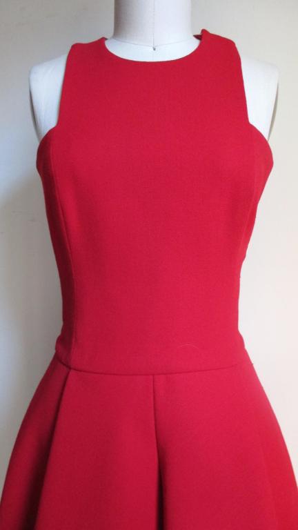 A beautiful red wool dress by Gianni Versace. It has great lines with square cut armholes, cut in shoulders, princess seam fitted bodice and fabulous flared skirt.  The skirt has 2 inverted front pleats in the front but the fullness comes largely
