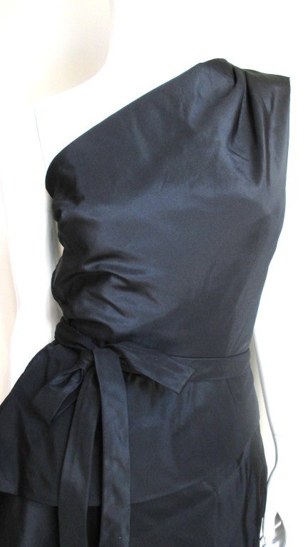 A beautiful dress from Werle, Beverly Hills in black silk. One shoulder with 3 pleats front and back coming into fitted bodice with an attached separate boned inner corset. The skirt is unique in that it is essentially one piece of fabric that wraps