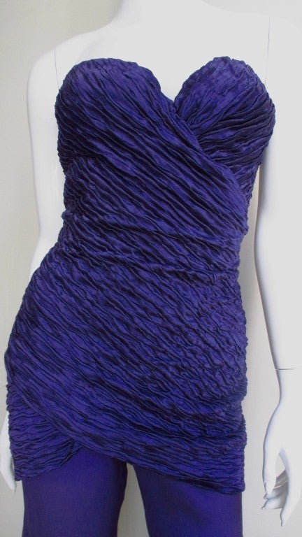 One of Versace's earlier masterpieces a fabulous silk jumpsuit with a crinkled texture boned bodice in purple.  The bustier bodice has built in under wire front crossing bra cups and then it is fitted through the body to thigh.  There is a separate