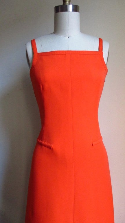 A orange cut-out back Maxi dress from Courreges.  From the front it is a simple A line with a square neckline, the back is low cut with 4 rows of vertical straps crossing and tied in the center.  Easy care polyester, matching side invisible zipper,