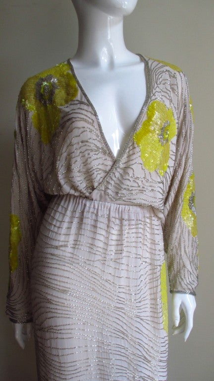 An absolutely beautiful silk set from Halston consisting of a long side slit skirt and matching wrap top.  Made of beige silk with large elaborately beaded and sequin yellow flowers randomly placed on a background of lines of silver glass beads. 