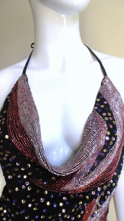 Fabulous halter top from Stephen Burrows in a lightweight black knit lined with a sheer black silk upon which are artfully placed rose shaded glass beads along the decolletage and down one side.  The remaining areas are dotted with gold and purple