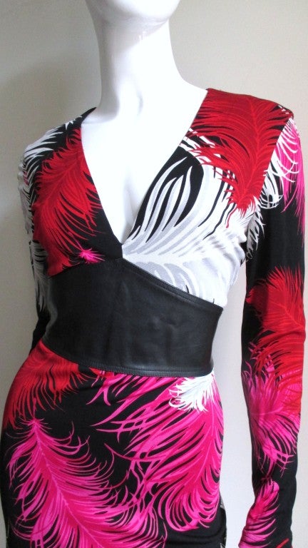 This is a stunning silk jersey dress from Gianni Versace Couture.  The colors are so vibrant- hot pink, red, white, grey and black fabulous feather pattern silk.  It has a plunge neckline which meets an inverted V black leather inset waist in the