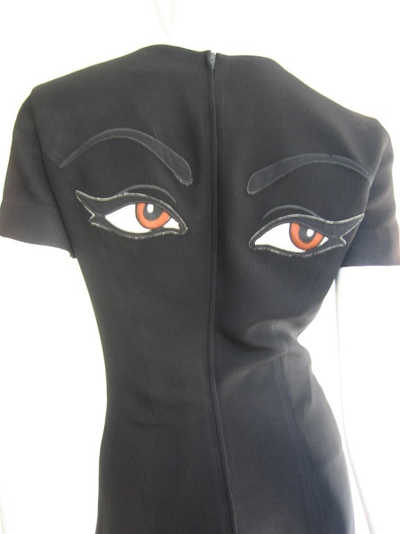 Simple black Moschino Couture shift dress from the front with great detail of large brown eyes and eyebrows in the back. Lined and zips up the back.  Excellent condition.  Size 8

Bust  35