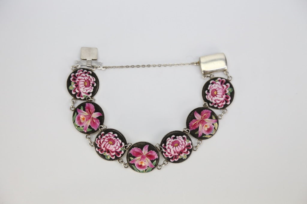 Beautiful Vintage signed Toshikane bracelet.  Seven alternating gorgeous hand painted embossed pink floral cameos of orchids and chrysanthemums detailed on black background; set in Sterling Silver mounting; signed TOSHIKANE JAPAN STERLING.  Push in