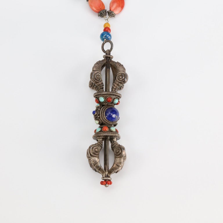 Favolosa collana unica nel suo genere, composta da turchesi naturali, corallo, lapislazzuli, agata e osso di varie forme e dimensioni intervallati da elementi in argento, che sospende un dorje tibetano in argento Sterling con corallo lapislazzuli e