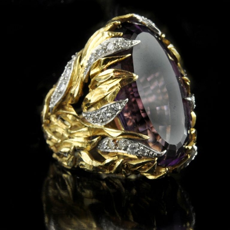 Impressive cocktail ring with a large central oval-cut amethyst engulfed by flames of yellow and white gold, with diamond accents. Grima, London 1964.