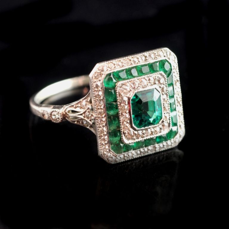 Edwardian emerald and diamond ring of square form with a central old-cut emerald with concentric borders of diamonds and emeralds to diamond-set shoulders and platinum shank English circa 1910.

PLEASE NOTE: OUR PRICE IS FULLY INCLUSIVE OF